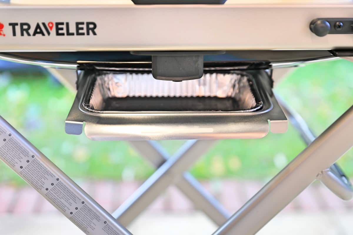 Photo of the underside of a Weber Traveler grill, showing the drip tr.