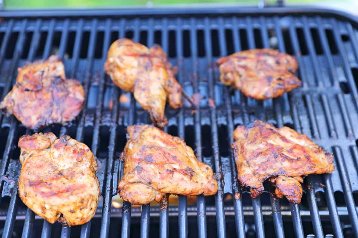 Six chicken pieces being grilled on a Weber Trave.