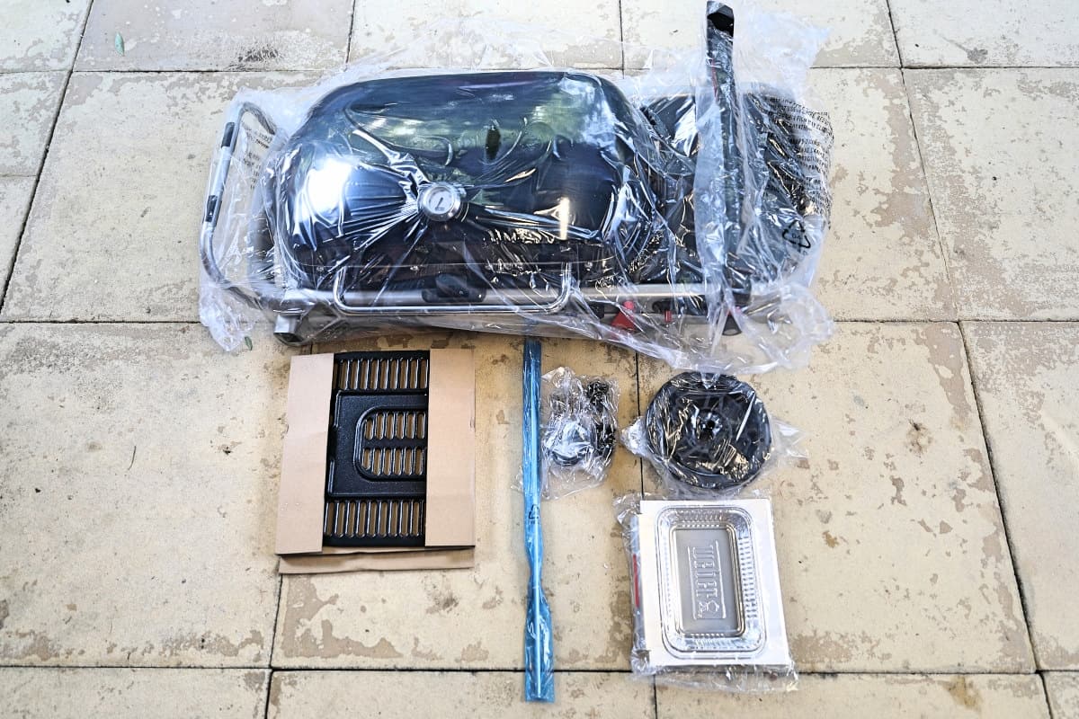 Contents of Weber Traveler box laid out neatly on a paved patio.