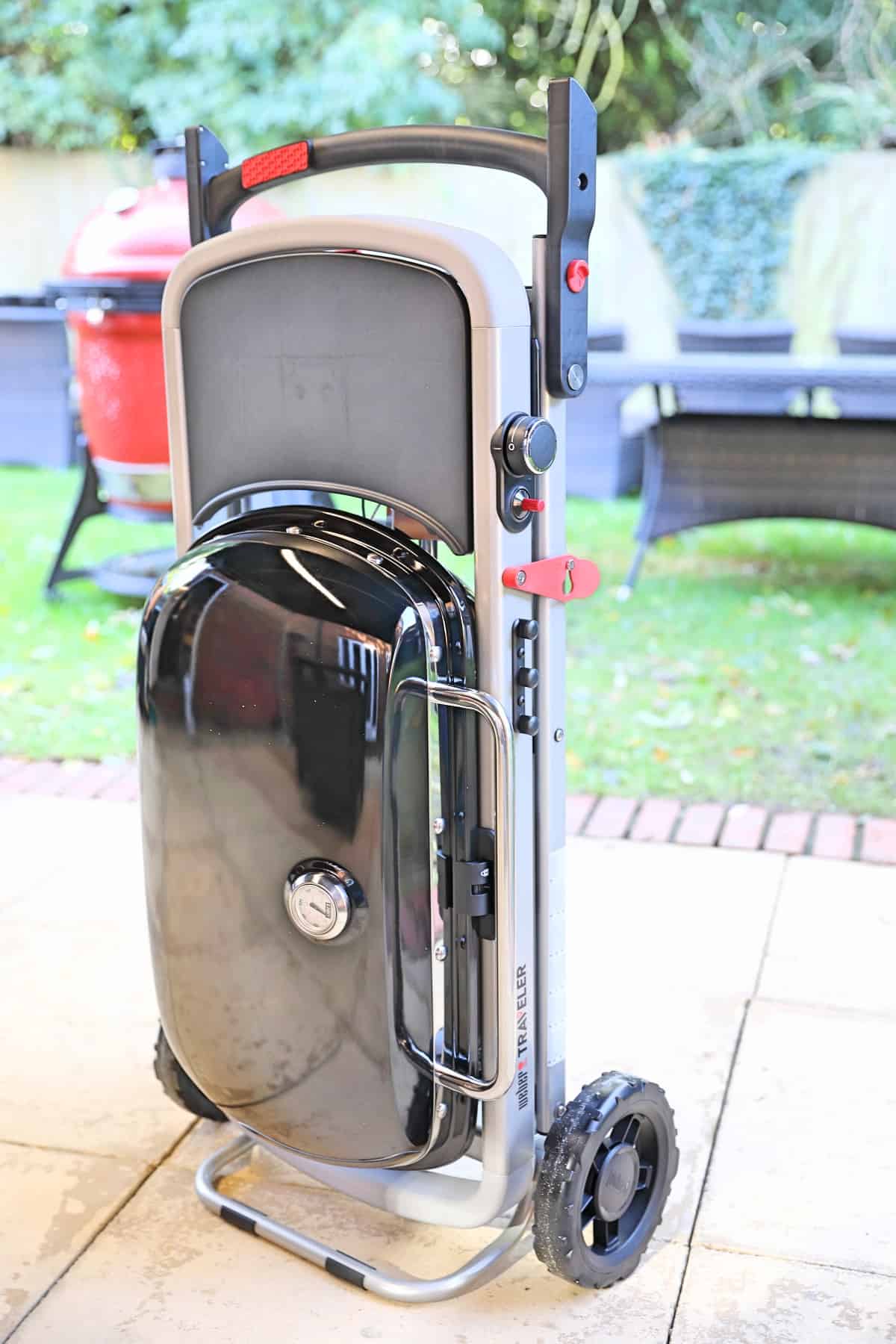 Weber Traveler gas grill assembled and standing upright on a paved patio.