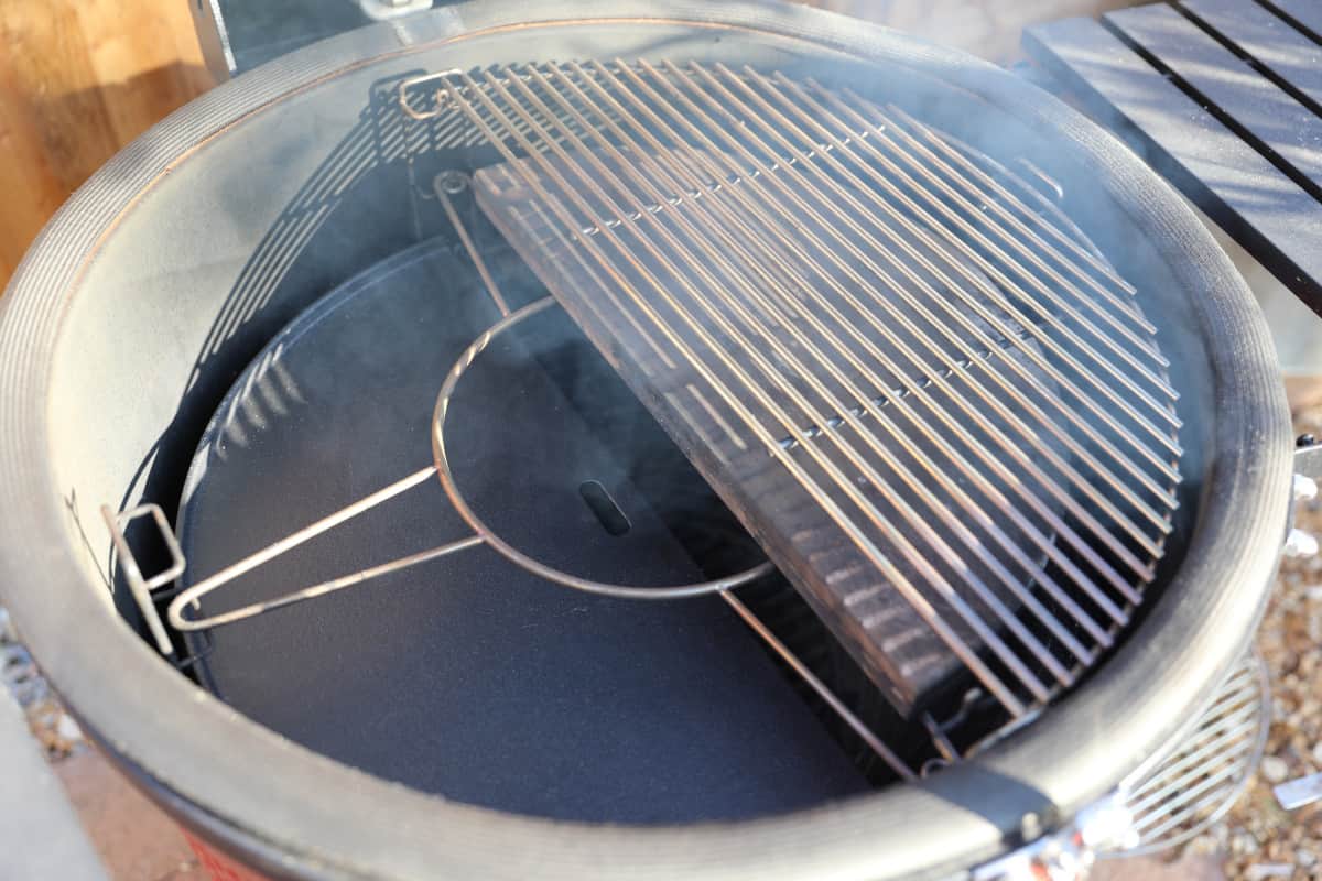 A close up of the Kamado Big Joe flexible cooking system with grates and a heat deflector inserted.