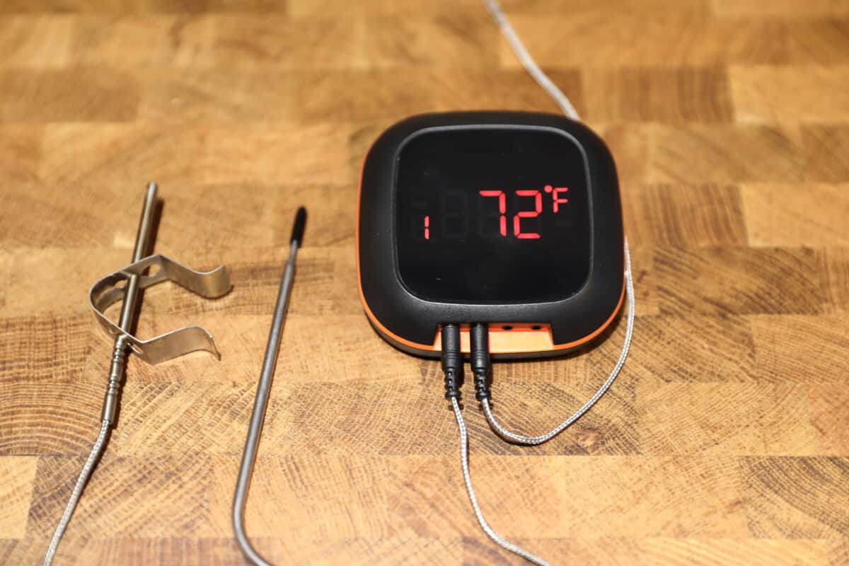 Inkbird IBT-4XS Bluetooth thermometer turned on, sitting on a wooden cutting board.