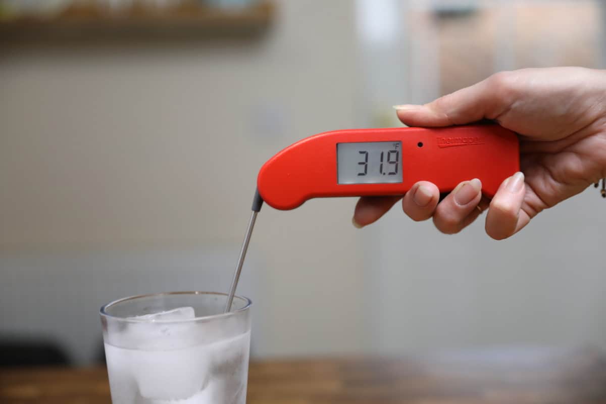 Thermapen one in a large glass of iced water, displaying 31.9 degrees Fahrenh.