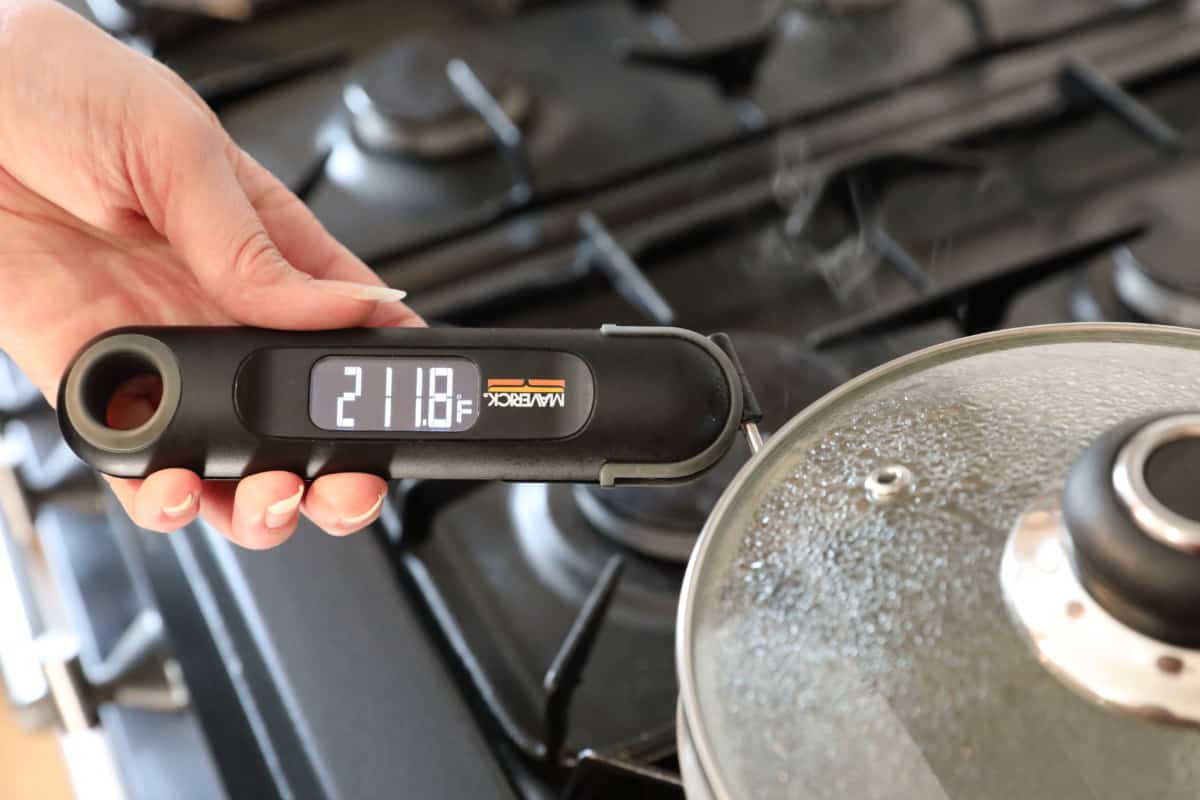 Maverick PT-75 being used to take the temperature of boiling water in a saucepan with a glass lid.