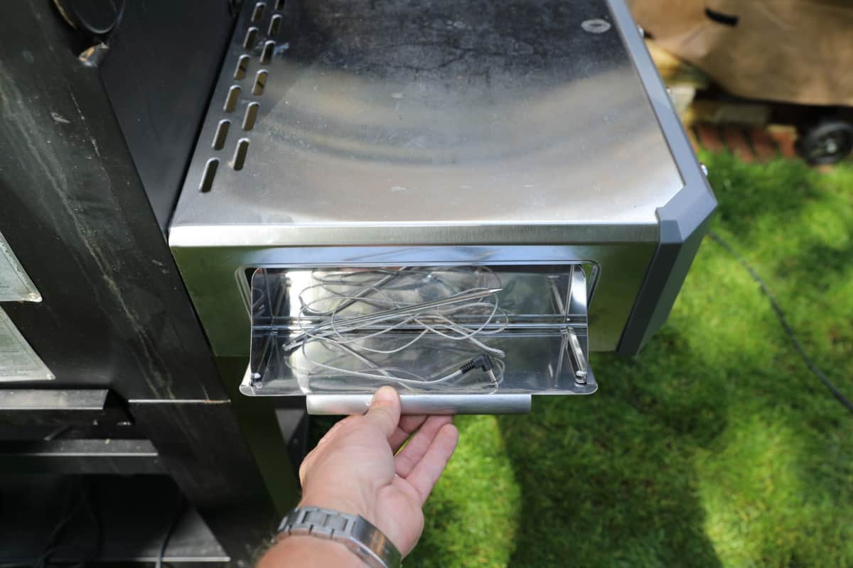 Masterbuilt gravity series side table drawer held open, with a thermometer probe ins.