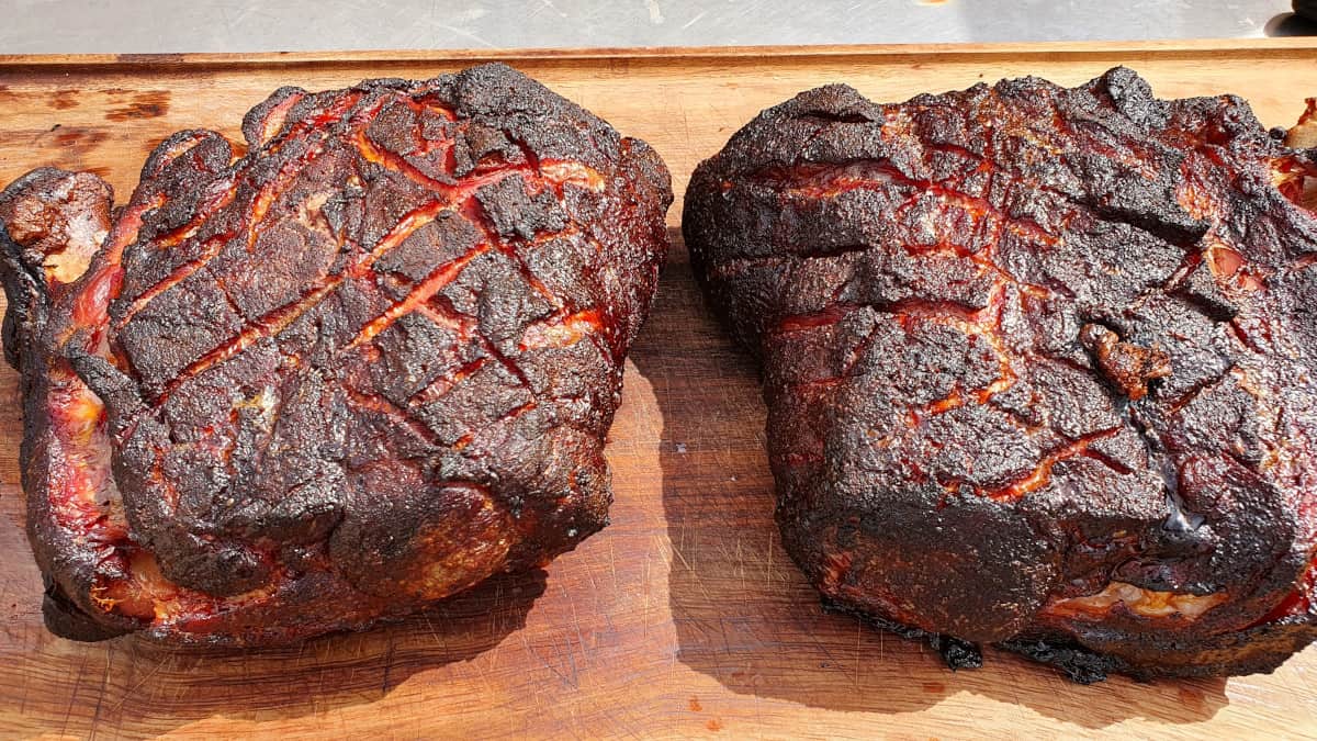 Two smoked pork butts on a wooden cutting board