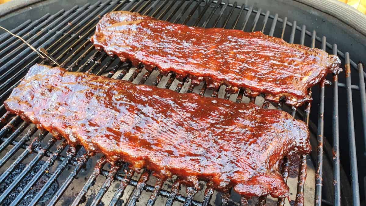 Two racks of pork ribs being smoked inside a Kamado Joe Big Joe III.