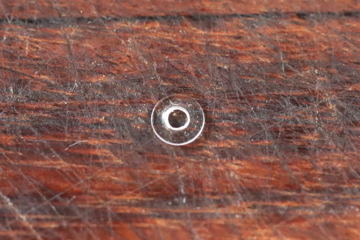 A small, see-through rubber washer on a wooden cutting bo.