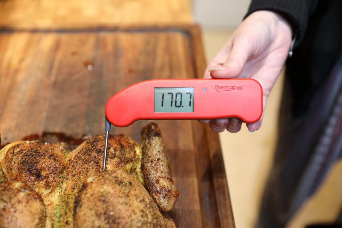 Thermapen ONE thermometer in a woman's hand, reading 170 degrees F of a chicken on a cutting board.