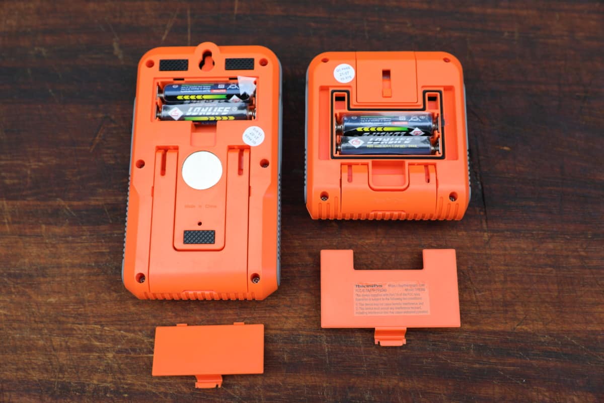The backs of the ThermoPro TP826 thermometer transmitter and receiver, with battery compartments removed, showing AAA batteries inside.