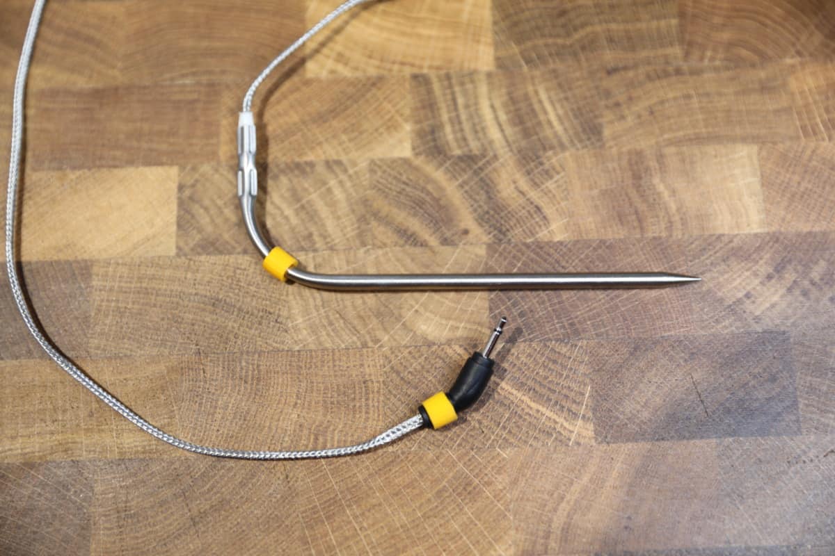 Weber iGrill 3 food probe, with yellow identification collars, on a wooden cutting board