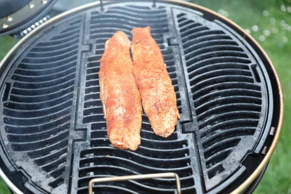 Pork tenderloin being smoke roasted on a charcoal grill.