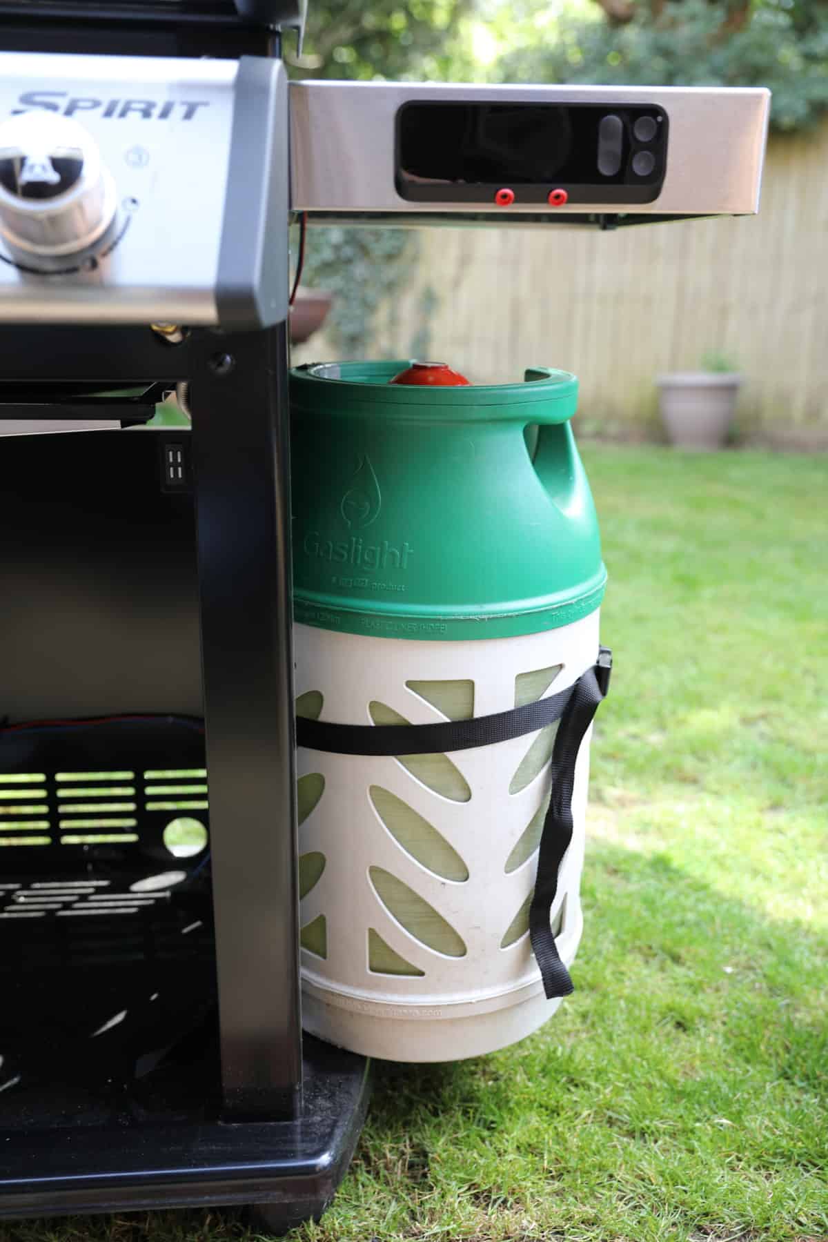 Close up of a gas canister strapped to the side of a Weber Spirit EPX-325S