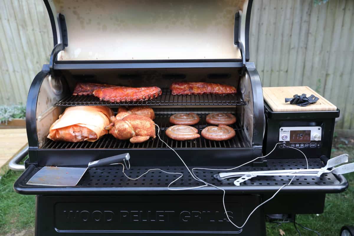 Z Grills 11002B pellet grill with lid open, loaded with ribs, chicken, sausages, and a brisket