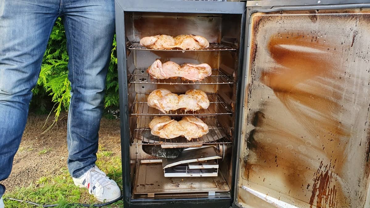 Masterbuilt electric smoker being used to chickens, with a mans legs in shot.