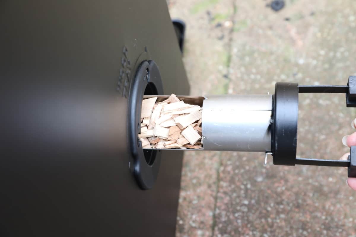 Wood chips being placed into the side of an electric smoker