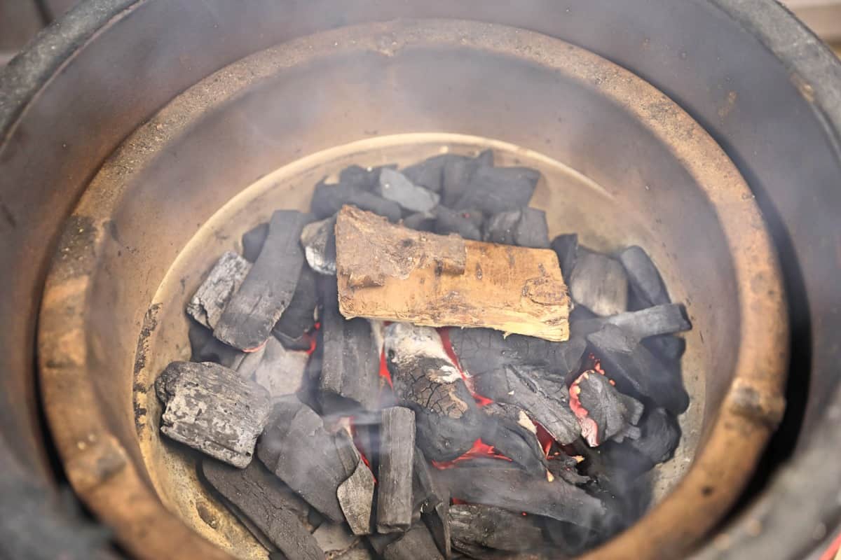 A chunk of cherry in lit charcoal, in a kamado joe jr