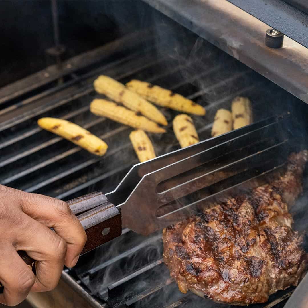 Baby sweetcorn and a steak being grilled in a gas grill with Grill Grates installed.