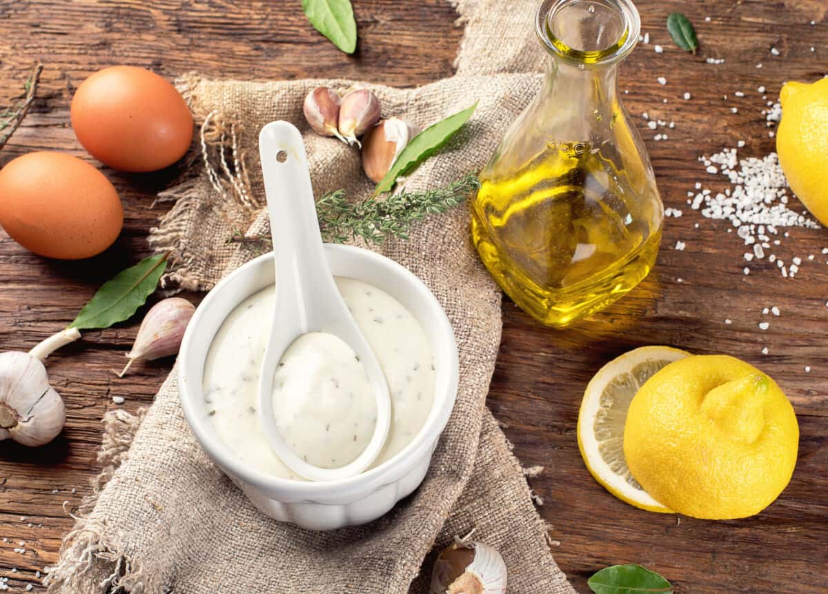 A small white bowl of aioli surrounded by the ingredients used to make.