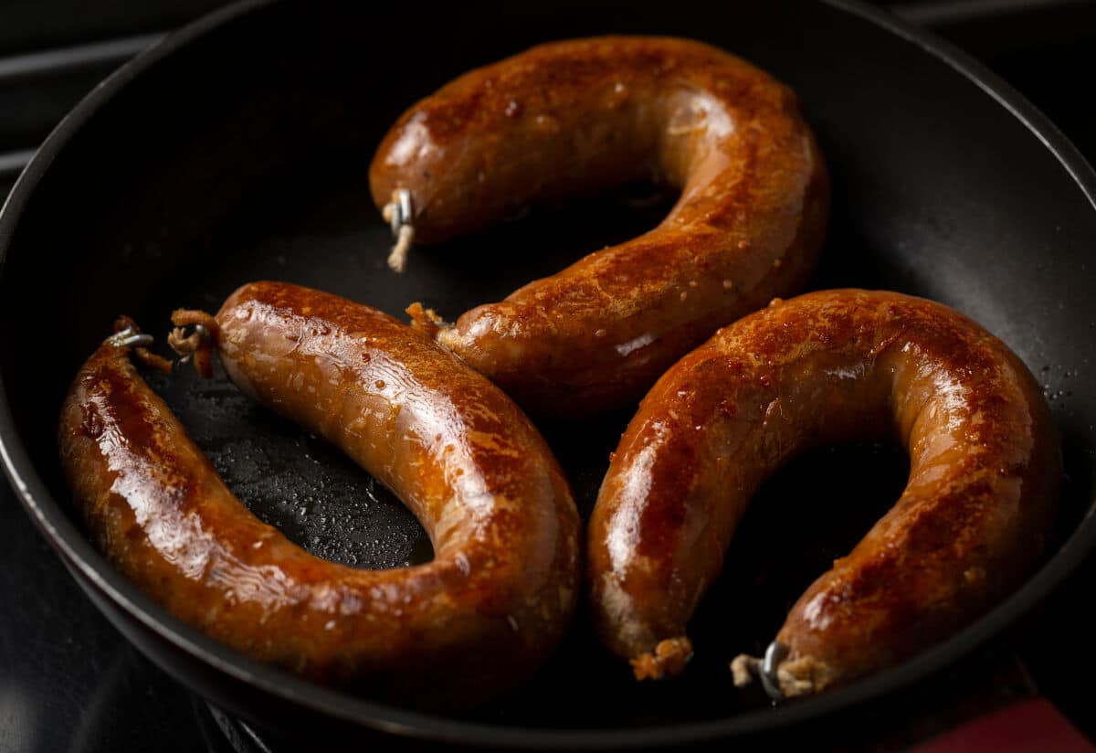 3 almost circular alheira sausages frying in a deep frying .