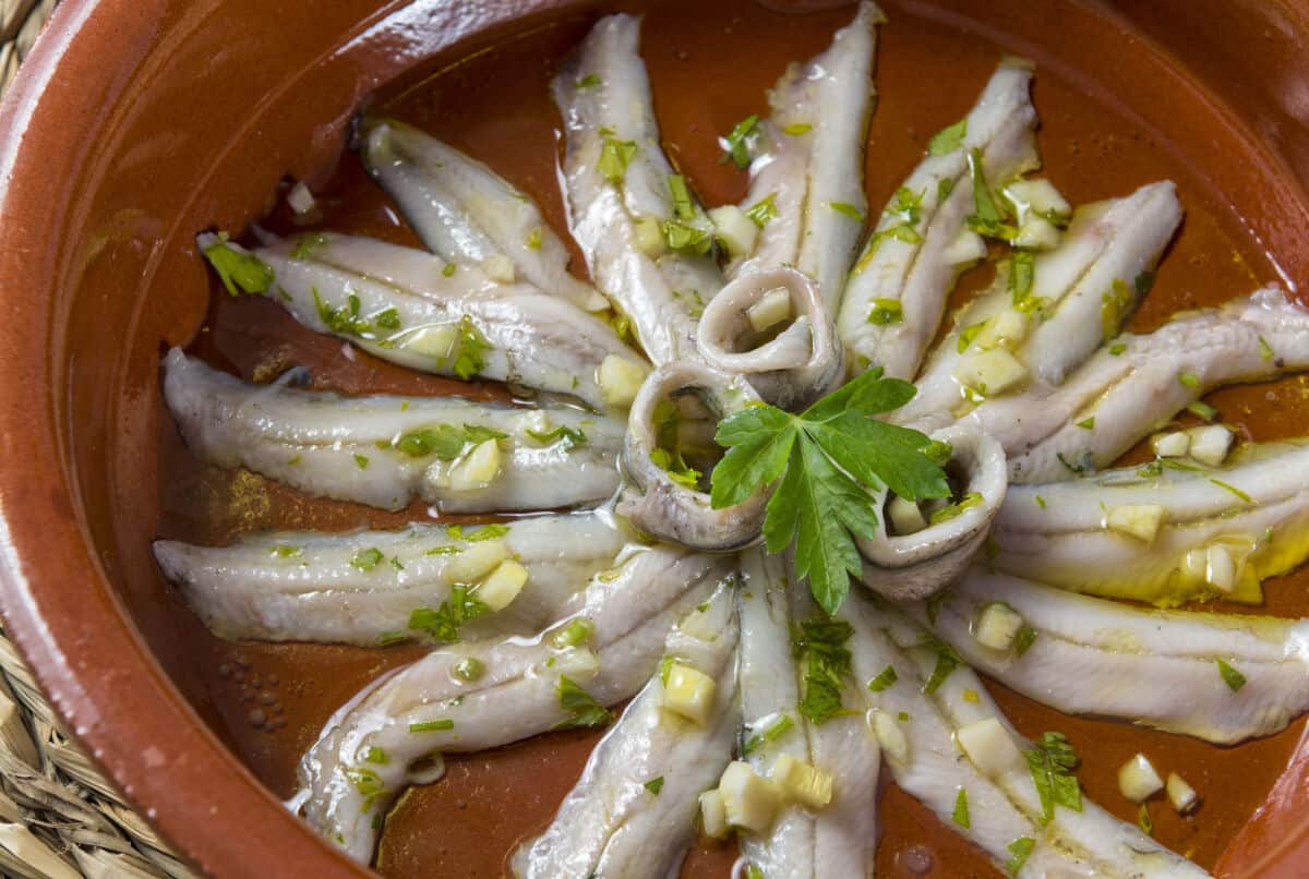 Marinated anchovies fanned out in a star shape, in a brown earthenware d.