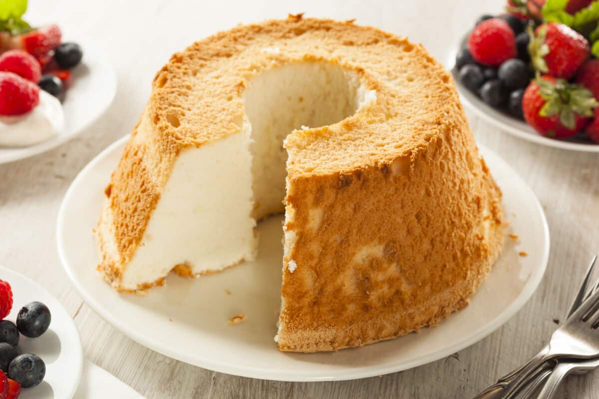A round angle food cake with a hole in the middle, a bit like a giant donut. With one slice removed, showing the almost pure white inter.