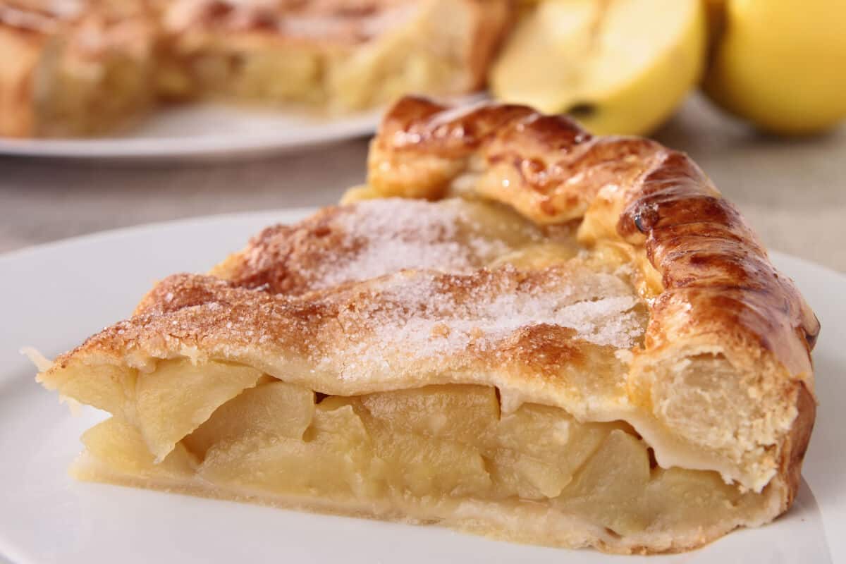 A large, thick slice of apple pie with thick pas.
