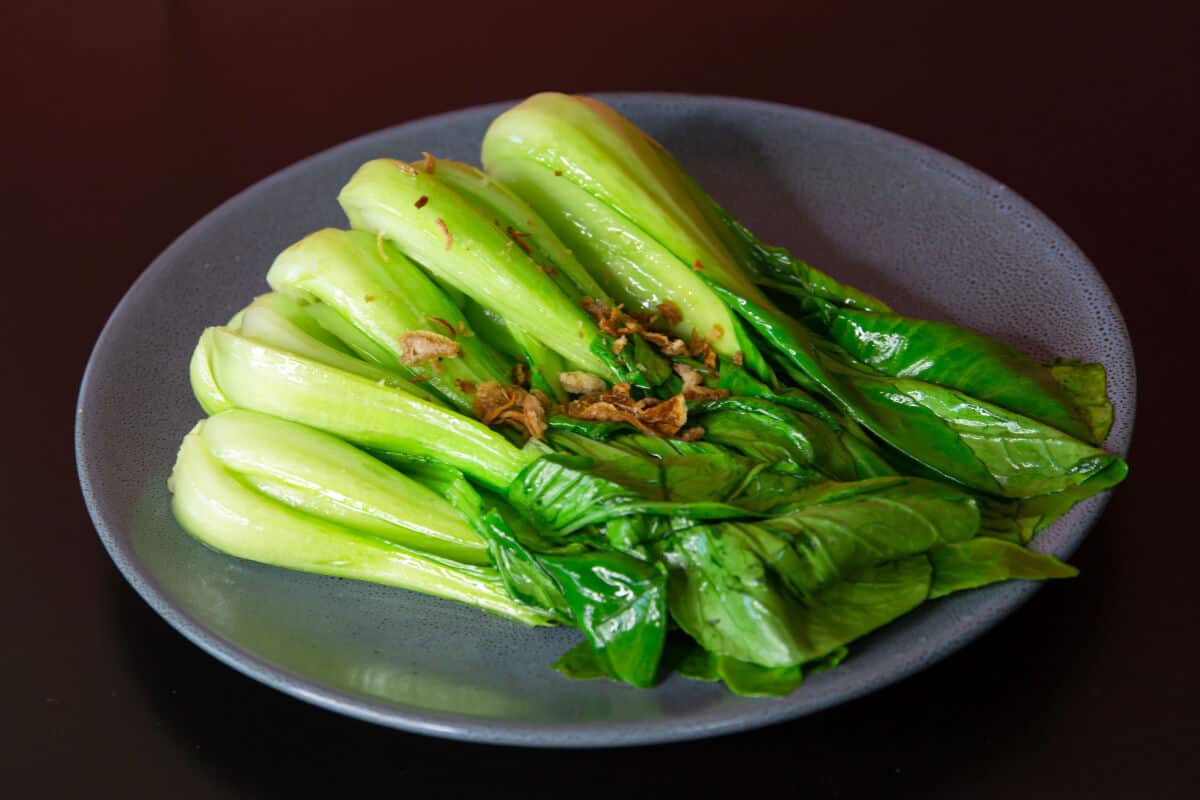 Stir fried, whole bok choy on a concave grey d.