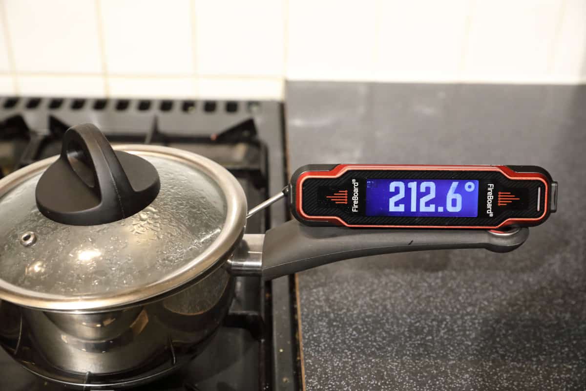 Fireboard Spark instant-read thermometer with its probe in boiling water, showing 212.6 degrees F.
