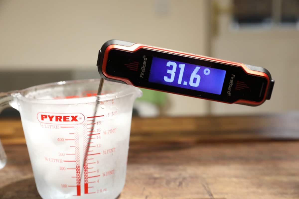 Fireboard Spark instant-read thermometer with its probe in iced water, showing 31.6 degrees F.