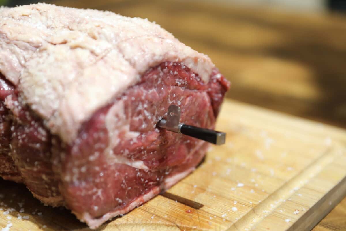 A Meater probe inserted into the side of a roasting joint of beef.
