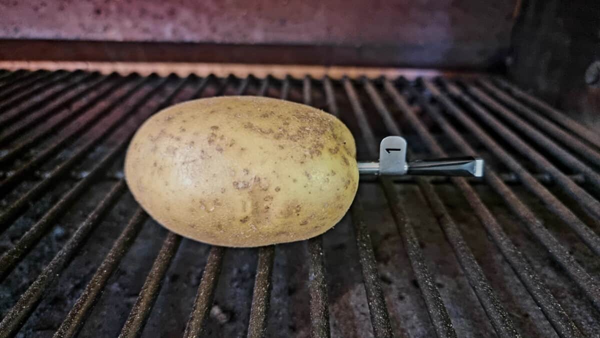 A MEATER Block probe inserted into a potato, sitting on a grill grate.