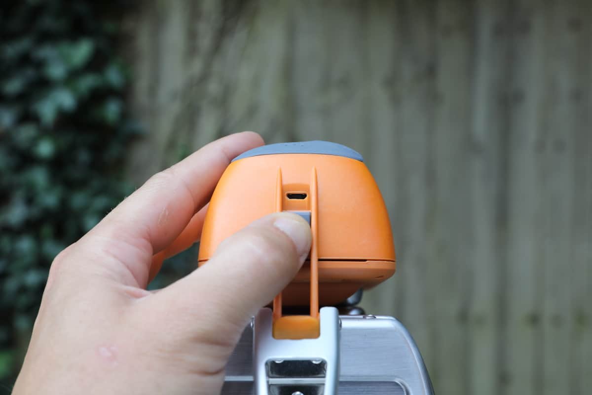 A mans hand showing the USB Micro connection underneath the battery pack of the Biolite CampStove.