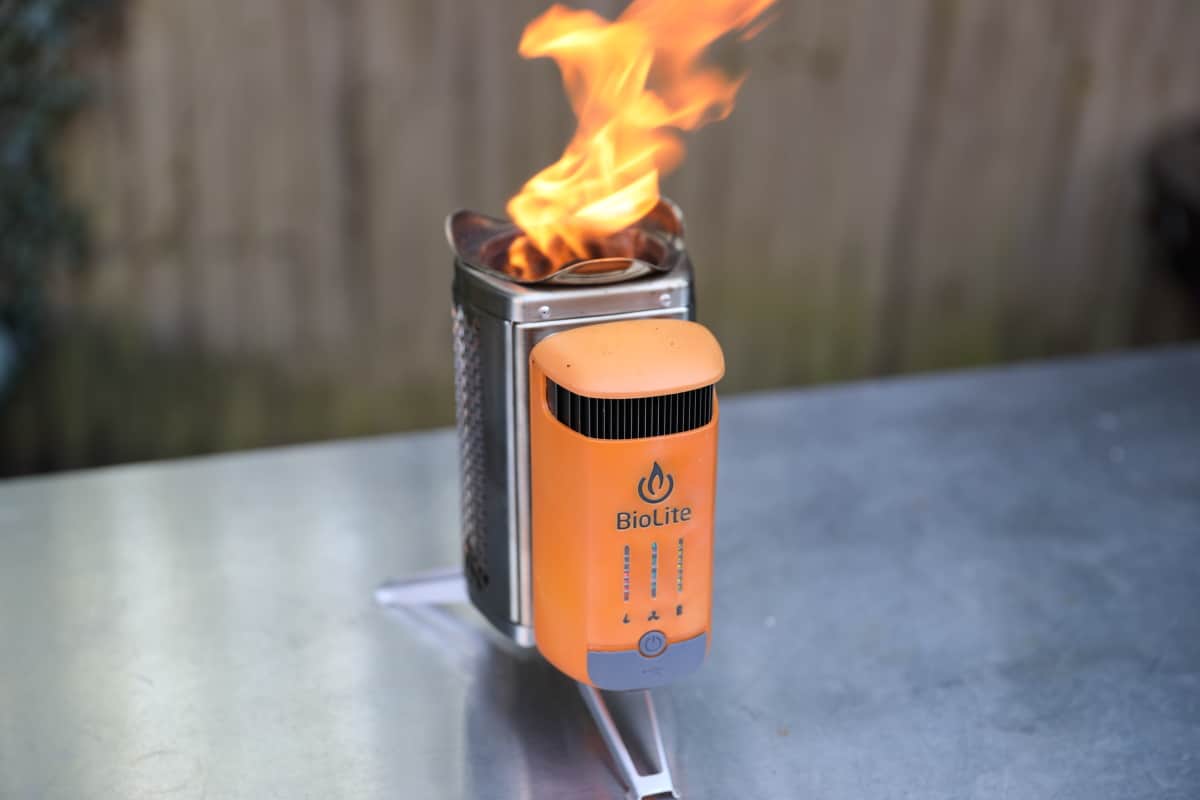 Biolite CampStove lit, with flames shooting out the top, sitting on a metal table.