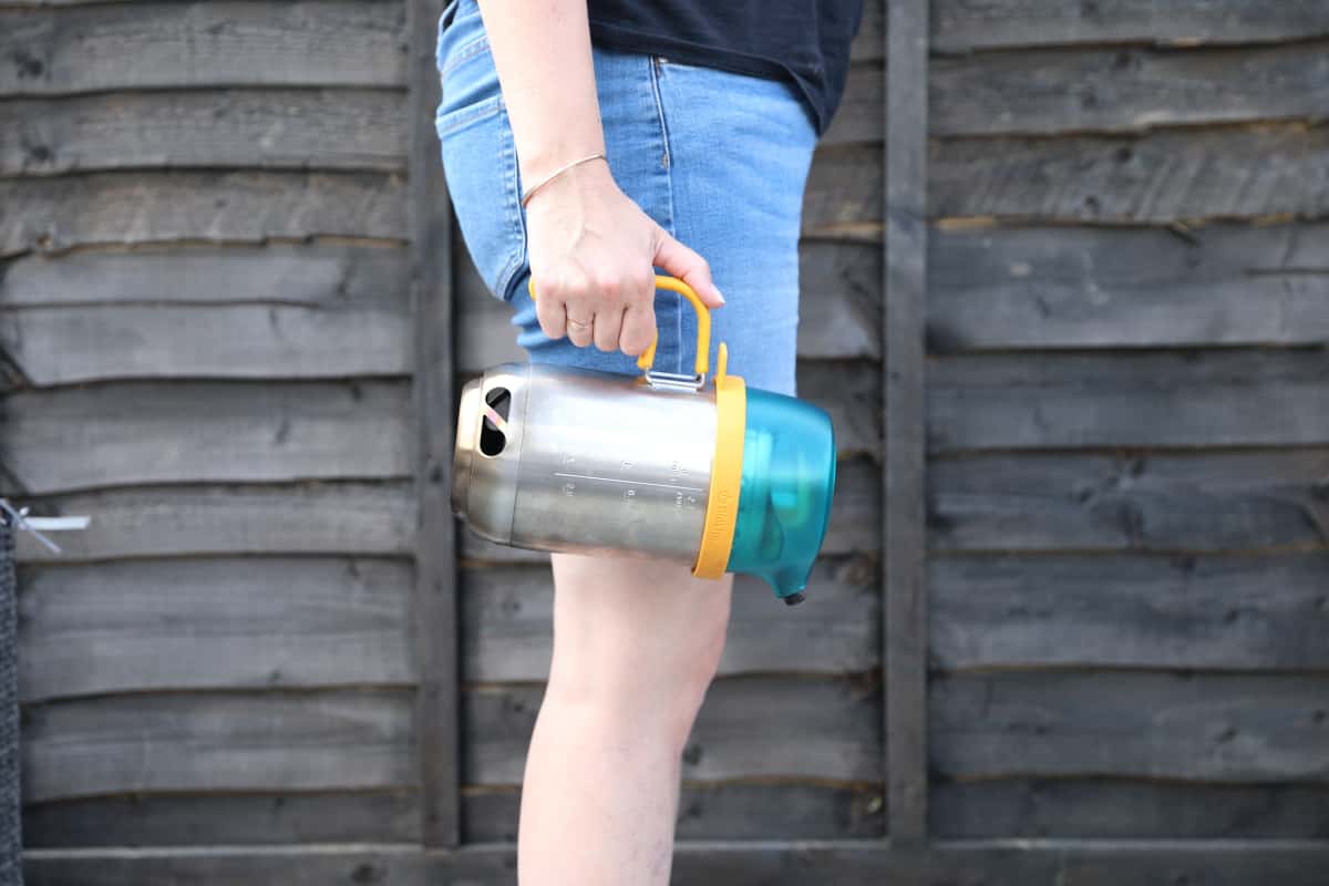 Biolite Campstove packed inside the Kettlpepot and being carried by a woman in denim shorts.