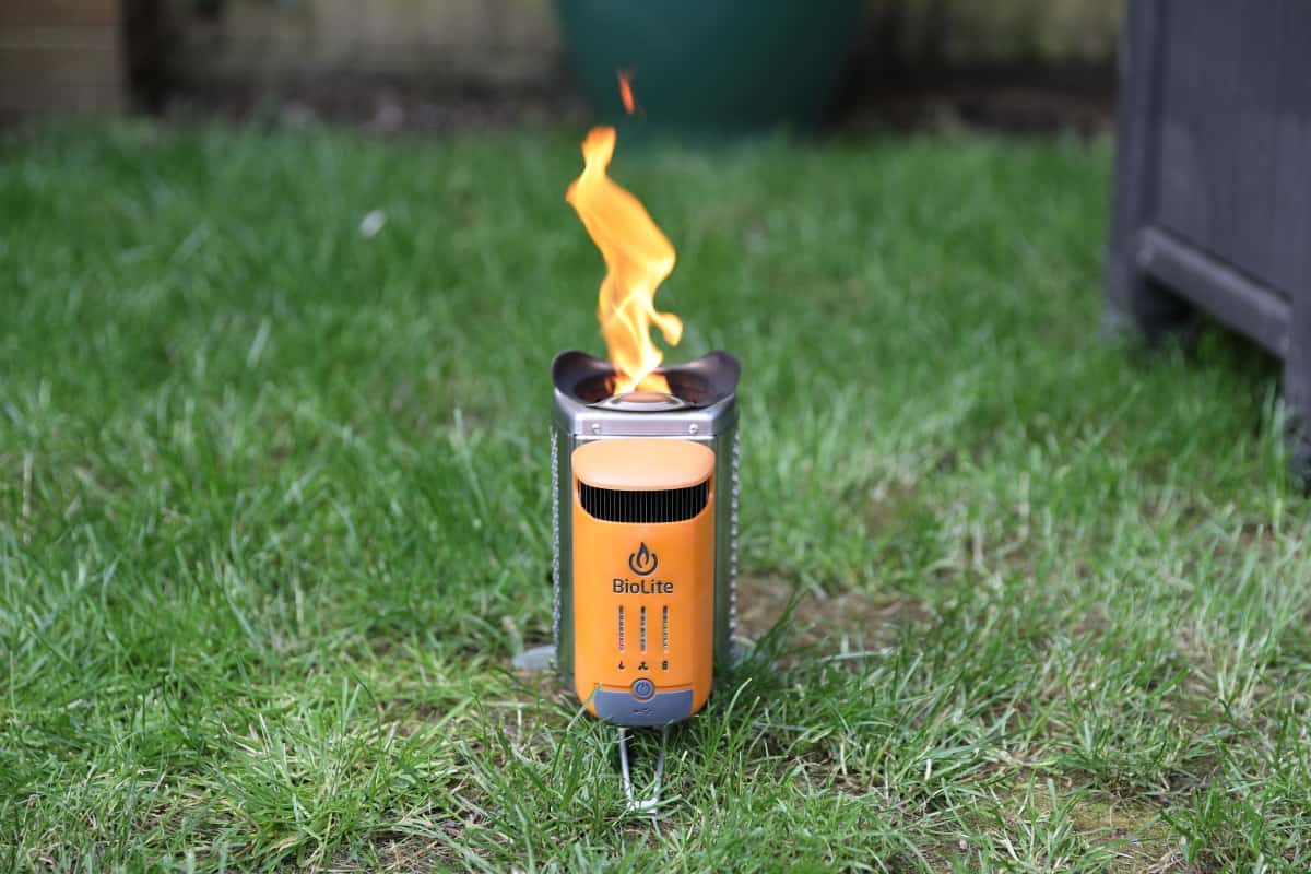 Biolite CampStove sitting on grass, with a large flames coming out of the top.