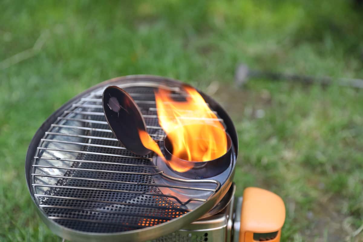 Biolite CampStove with grill accessory attached, and large flames coming out of the chimney.