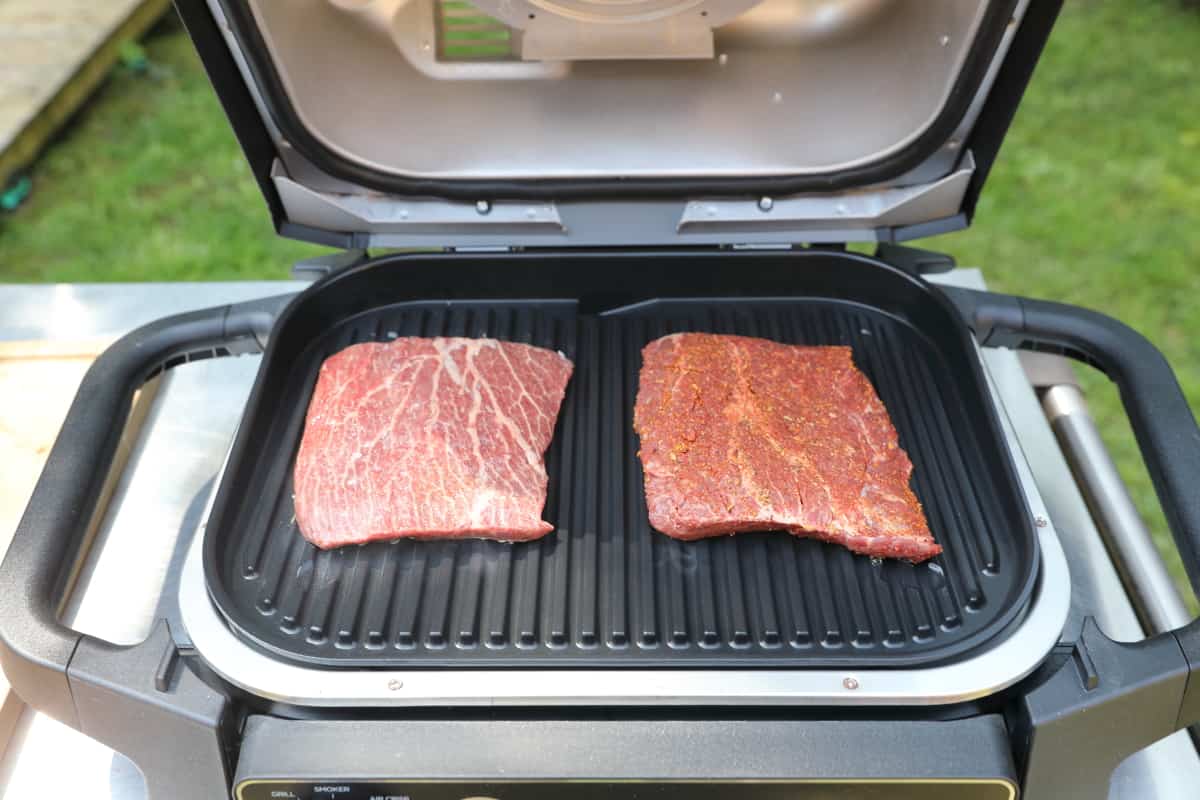 Two raw steaks sitting on the grate of the Ninja Woodfire.