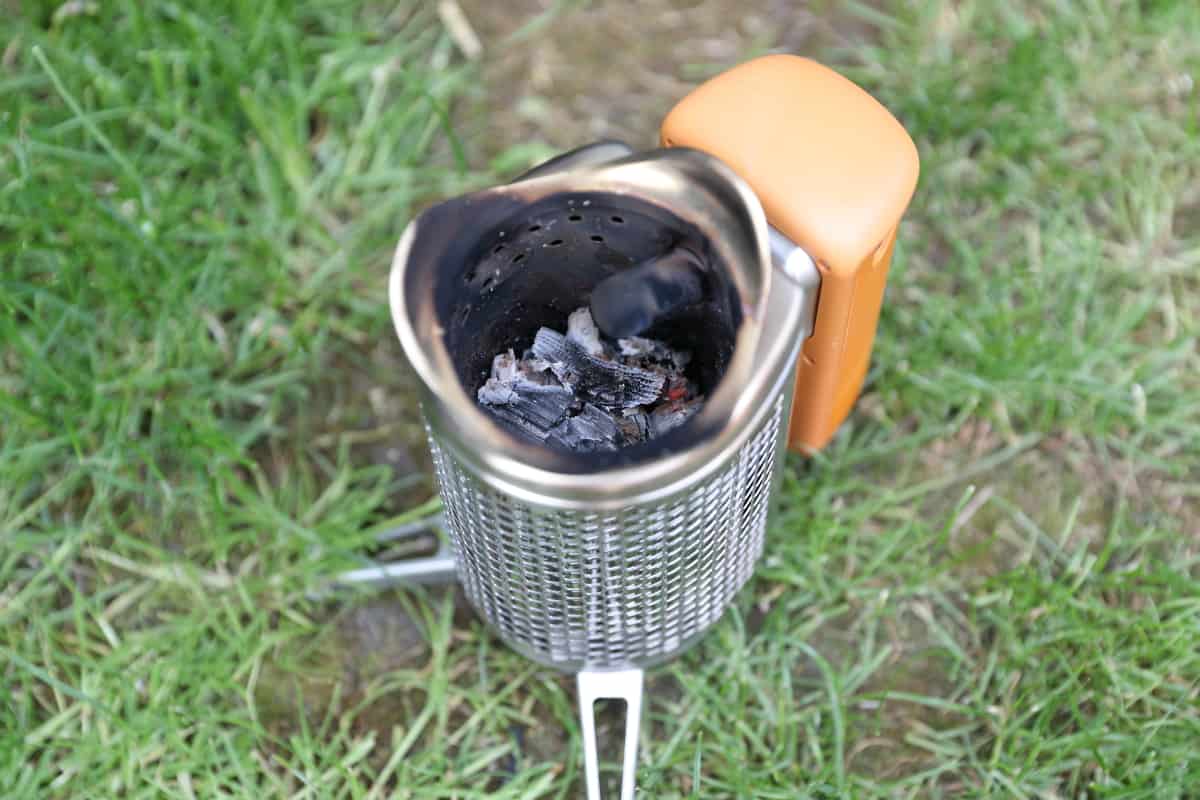 Biolite CampStove half full of ashes, sitting on grass.