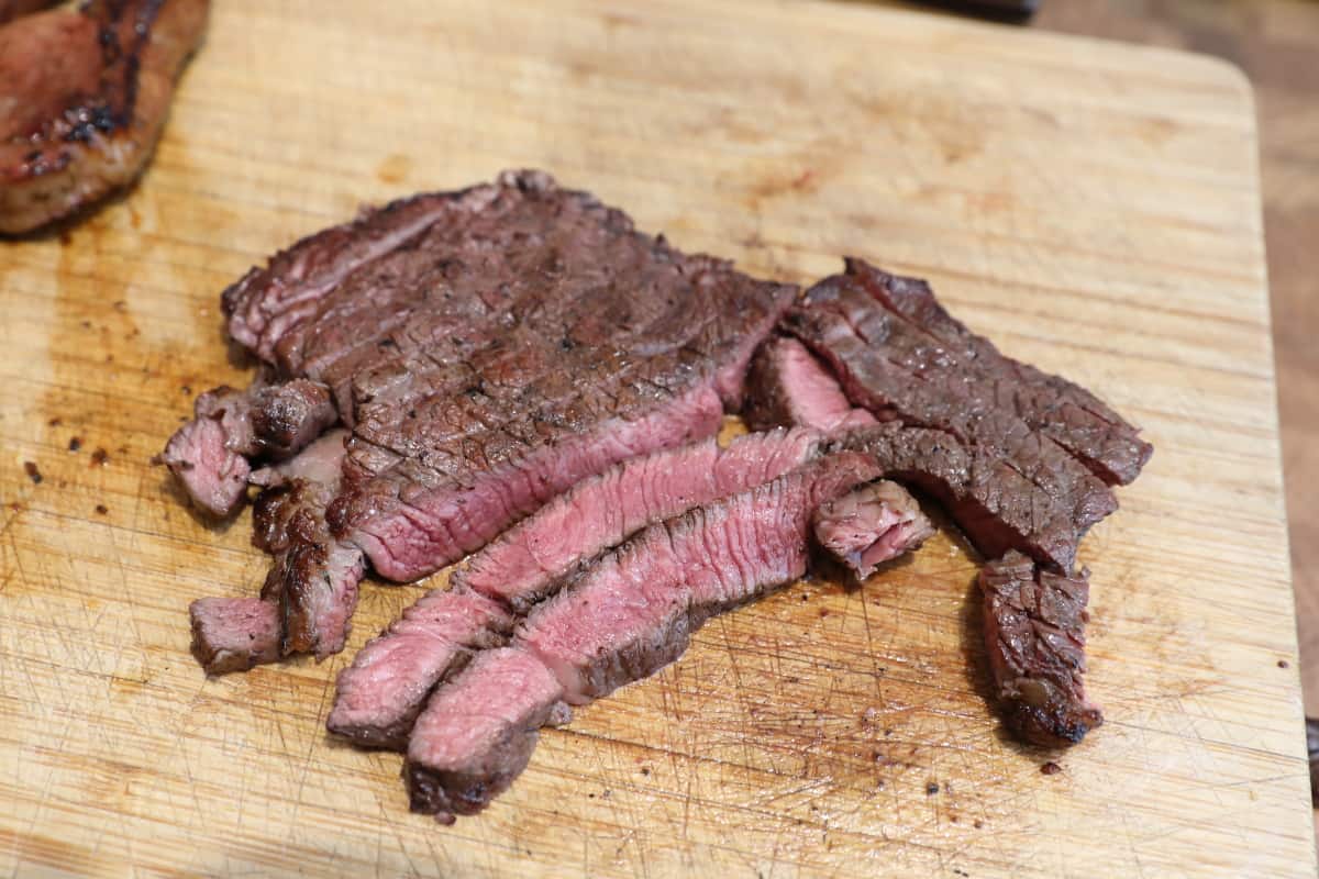 A sliced medium-rare steak on a cutting board, showing a good sear and a nice pink middle.