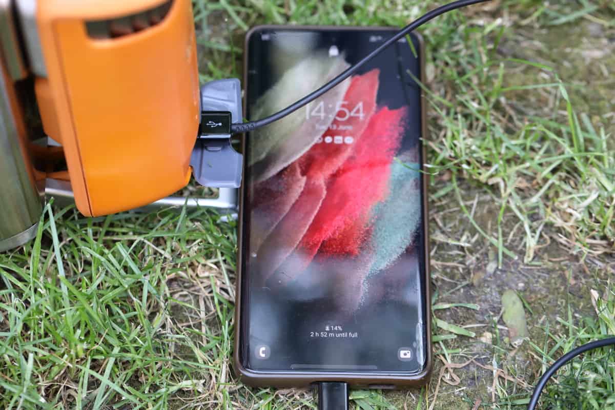 A mobile phone charging from a Biolite CampStove.