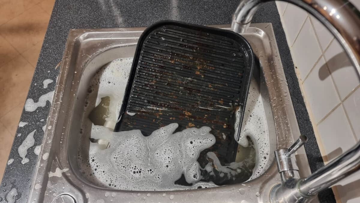 Ninja Woodfire grill grate in a sink full of soapy water.