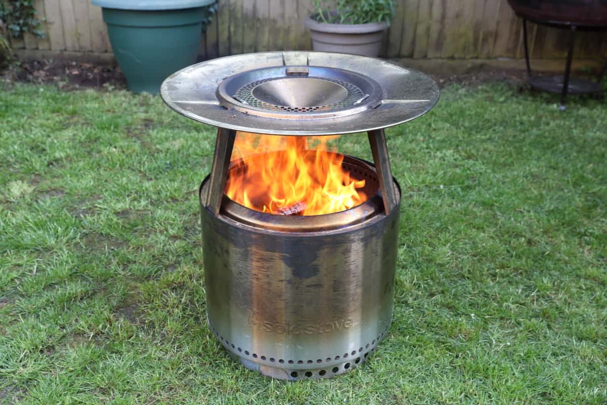 Solo Stove Bonfire with Heat Deflector fitted and a fire burning inside.