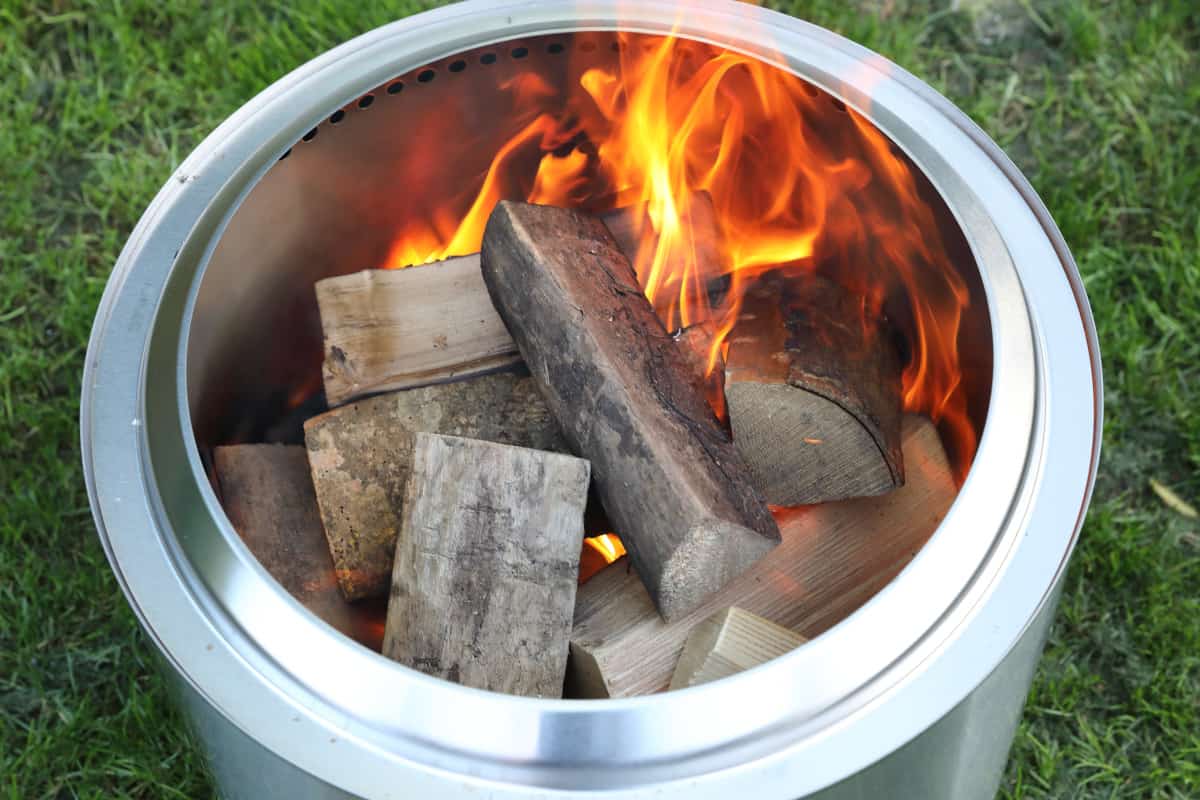 Solo Stove Bonfire full of logs and starting to burn with small flames.