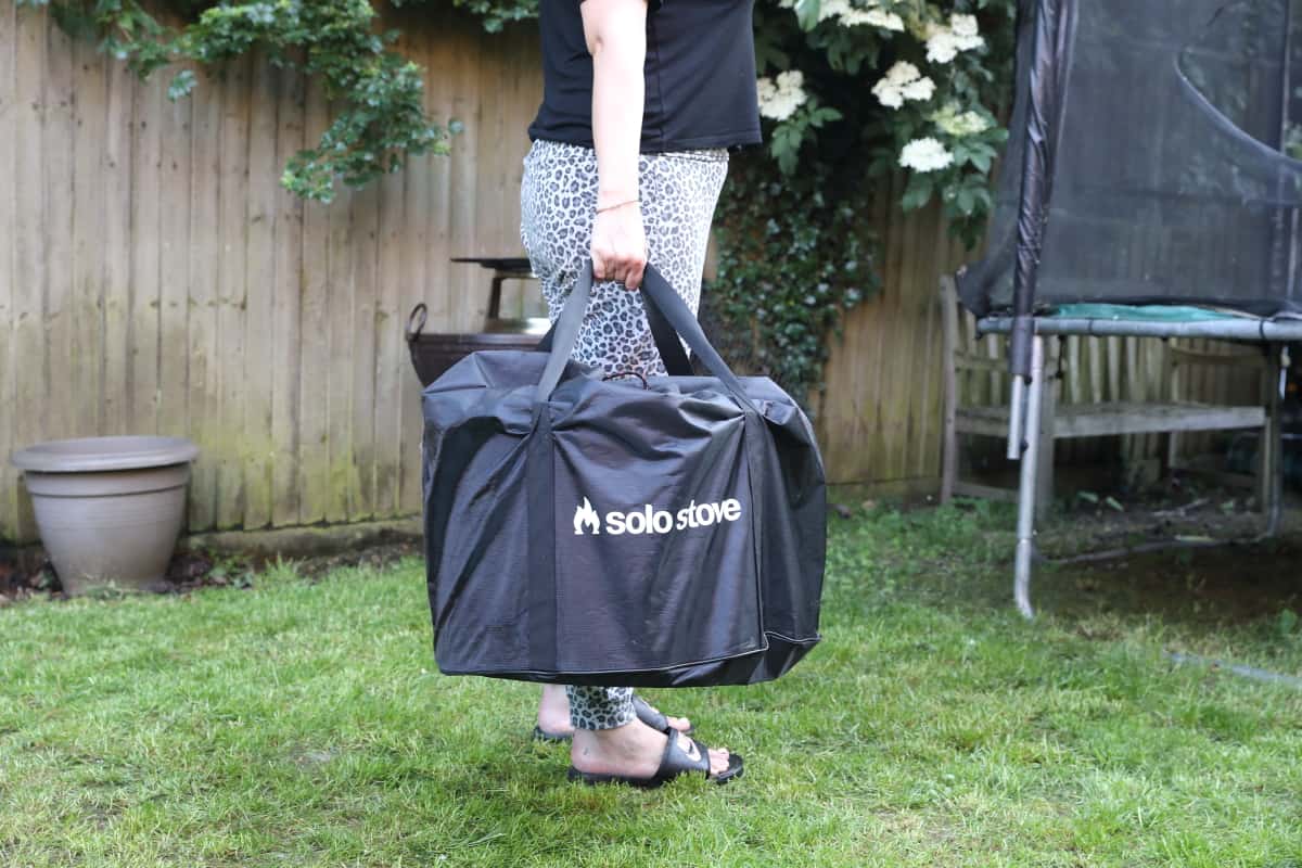 Woman carrying a Solo Stove Bonfire in the available bag.