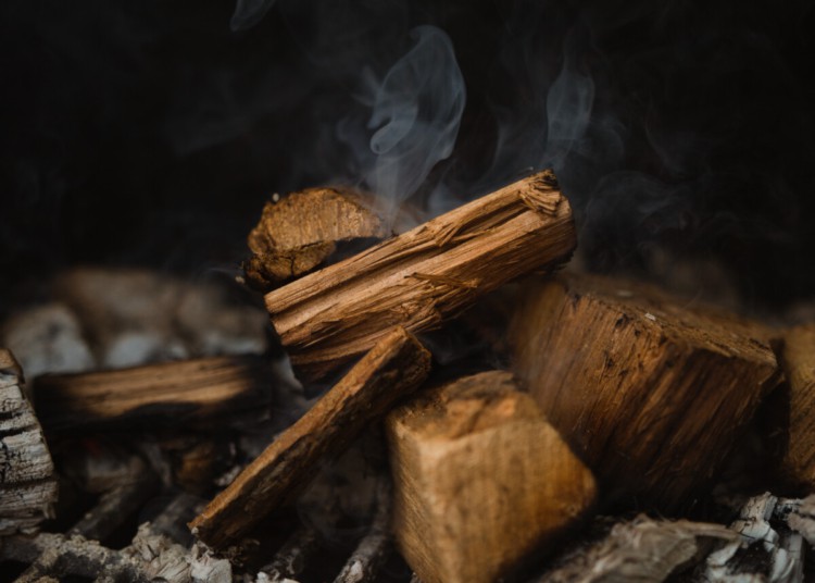 Some slowly smoldering hickory wood chunks sat on charcoal.