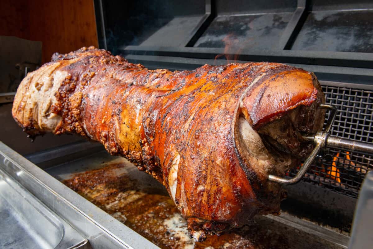 A pig roaster with the body of a pig on a rotisserie.