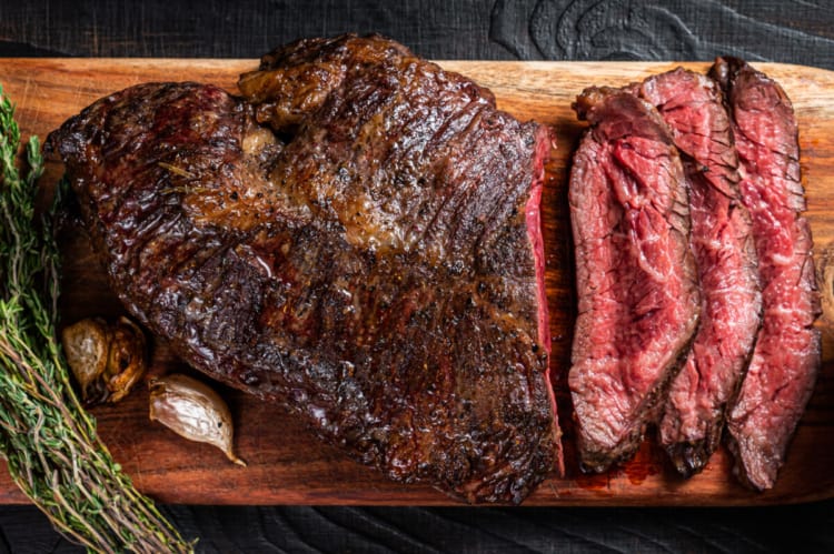 Grilled onglet steak, partially sliced, sitting on a cutting board.