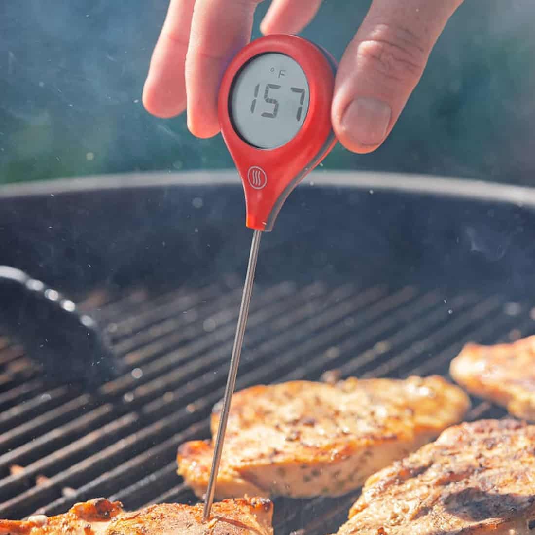 ThermowWorks ThermoPop 2 thermometer taking the temperature of some meat on a grill.
