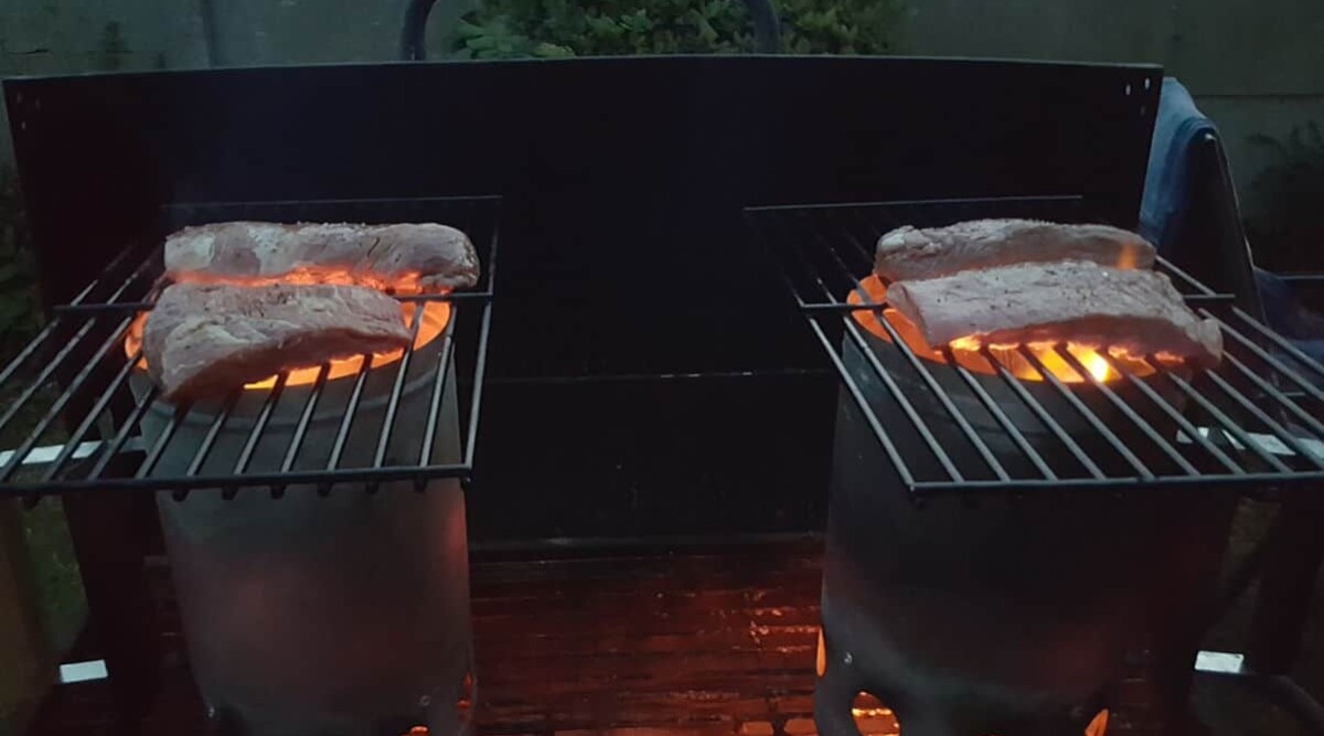 Afterburner steak grilling on top of two charcoal chimneys.